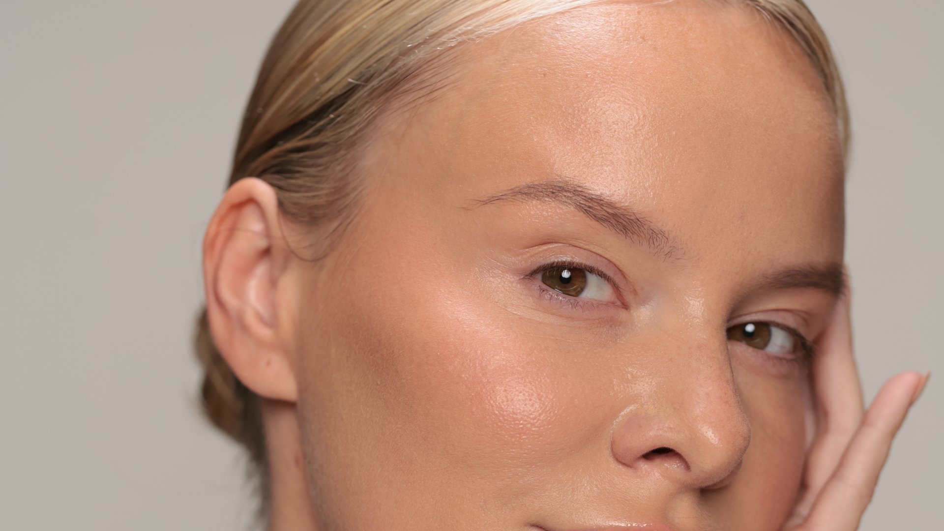 A hydrated, luminous complexion framed by the hands.